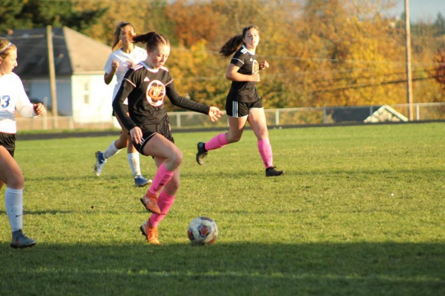 Last year's soccer games looked much different than this year. In this photo from last school year, student Hannah Jolly kicks the ball in a game against Blanchet. This year, soccer students are required to wear masks while competing. 